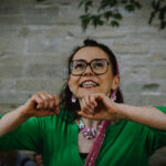 Erzählerin Tanja Schreiber mit langen schwarzen Haaren, Brille und in einem grünen Kleid erzählt Märchen bei einer Märchenwanderung