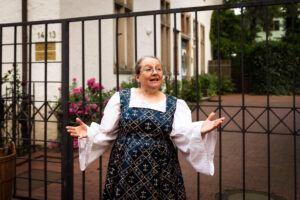 Erzählerin Sabine Meyer im blau weißen Kleid erzählt Märchen in der Osnabrücker Altstadt, hier Superintendentur im Rahmen der Märchenwanderung