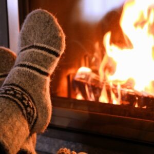 Kamin mit brennenden Holzscheiden, Flammen, Füße mit Wollsocken