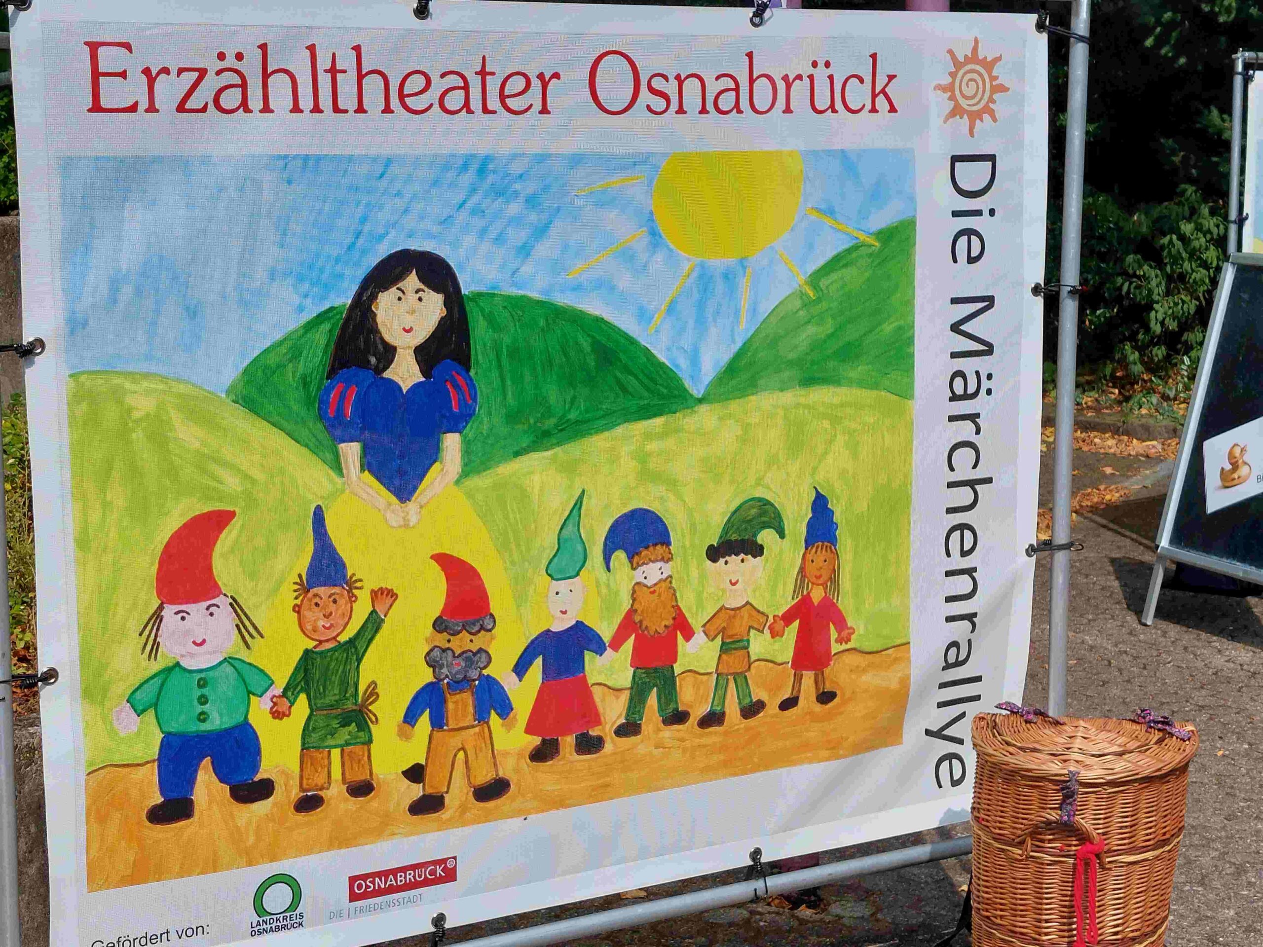 grüne Wiese, Märchenaufsteller vom Erzähltheater Osnabrück, Motiv: Schneewittchen und die sieben Zwerge, Kiepe aus Rattan, Märchenralley draußen